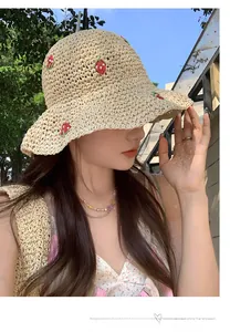 Close-up of beige straw sun hat featuring detailed red and green strawberry embroidery