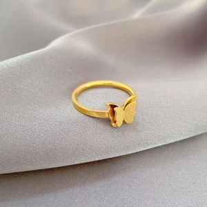 Macro detail of golden butterfly ring featuring textured wings on silk background