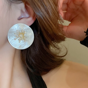 Gros plan d'une boucle d'oreille fleur en perle sur mannequin avec détails dorés en zircon