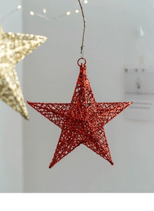 Detail of red hollow glitter star ornament hanging with festive warm lighting background