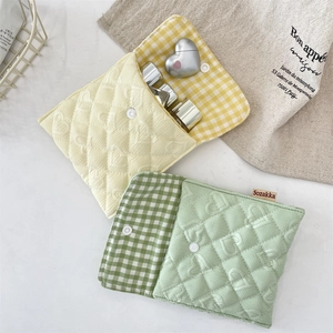 Close-up of quilted heart pattern storage pouch with snap button and checkered lining