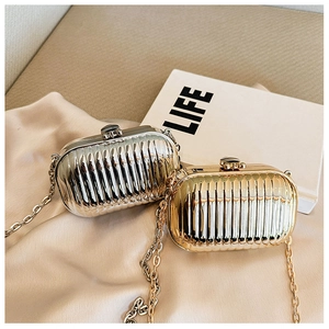 Close-up of gold and silver metallic clutch bags with chain on luxury silk background