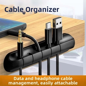 Detailed view of black 5-slot silicone cable manager fixed on desk edge with adhesive
