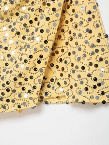 Detail of yellow sequin mini skirt with silver and black wavy pattern embroidery