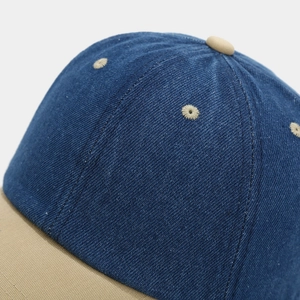 Macro view of blue denim baseball cap with khaki brim showing twill fabric and stitching