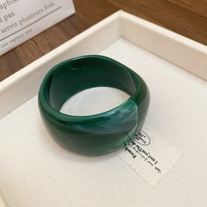 Detail of wide resin bangle with dark green marble texture on a white tray display