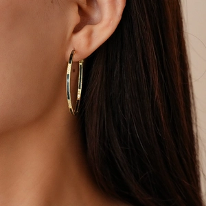 Gros plan d'une boucle d'oreille créole géométrique plaquée or 14 carats et émail noir