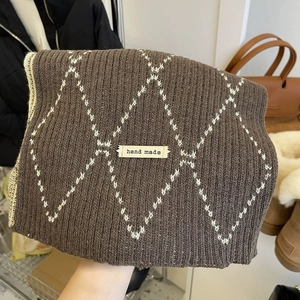 Detail of soft knit plaid scarf in dark brown with white diamonds and hand made tag