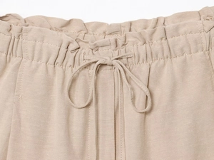 Detail view of the drawstring elastic waistband on light khaki linen blend shorts