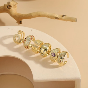 Detailed display of five 14K gold-plated rings with colorful gemstones on a textured stand