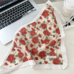 Close-up of a 100% cotton floral headscarf with white lace edges on a bright desk