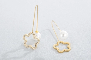Close-up of golden four-leaf clover earrings with sparkling rhinestones and elegant pearls