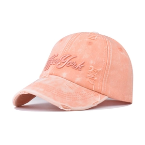 Close-up of pink washed cotton baseball cap with New York embroidery and distressed holes