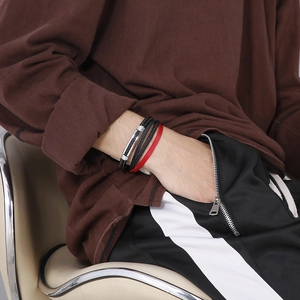 Detail of multi-layer black and red braided leather bracelet with silver magnetic clasp on wrist