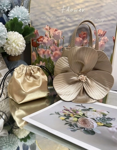 Close-up of champagne gold petal tote with drawstring pouch and pearl center detail