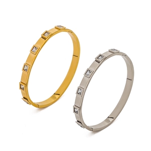 Close-up of gold and silver steel bangles with square zircon inlay geometry