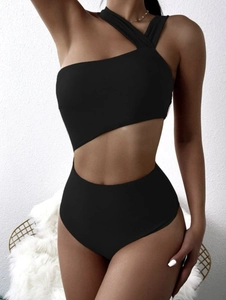 Detail view of the asymmetrical cutout waist and one-shoulder strap of the black swimsuit