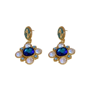 Vintage baroque floral earrings with blue crystals and gold metal on white background