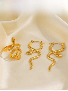 Detailed view of polished golden snake-shaped ring and earrings set on velvet background
