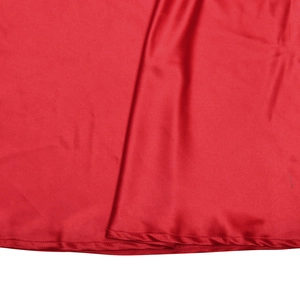 Gros plan détaillé du tissu en satin rouge brillant avec ourlet cousu et plis soyeux