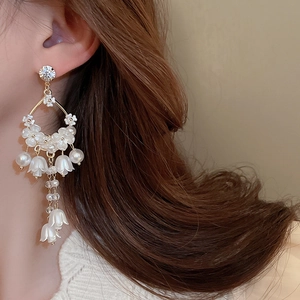 Detailed close-up of lily of the valley tassel earrings with pearls on model