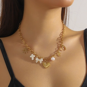 Golden stainless steel necklace with sun, cross, bow, and pearl charms worn by a model