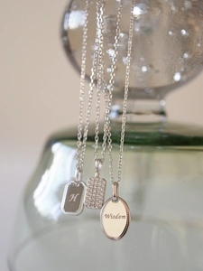 Macro shot of S925 silver pendants with H initial, sparkling pavé stones, and Wisdom engraving