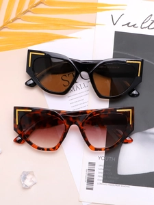 Detail of oversized cat-eye sunglasses with golden L-shaped metal corner decorations