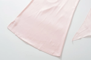 Close-up of the light pink satin dress hem showing premium silk texture and fine stitching