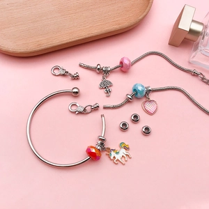 Detailed flat lay of silver open bangle and snake chains with colorful unicorn beads