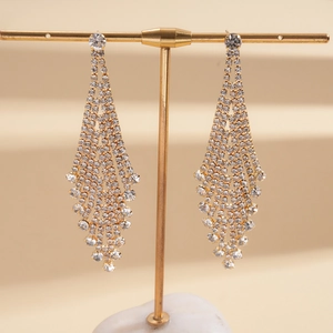 Close-up of long gold fringe tassel earrings with white rhinestones on display stand
