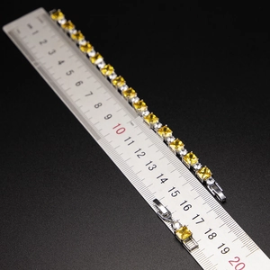 Close-up of a silver bracelet with yellow square zircons and ruler showing its 18cm length