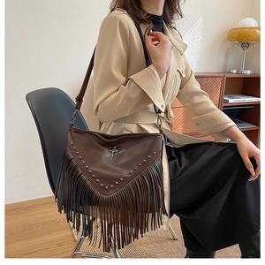 Détail d'un sac à bandoulière en cuir PU marron avec franges, rivets et pendentif croix