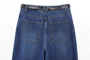 Dettaglio retro vita dei jeans denim blu scuro con cintura nera e cuciture tasche