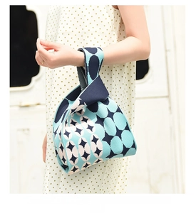 Minimalist geometric knit handbag with navy and beige patterns held by a model