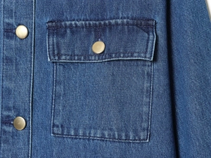 Dettaglio giacca in denim con colletto in velluto, tasca sul petto e bottoni metallici