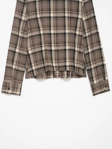 Detail view of plaid shirt hem and buttoned cuffs in brown and beige patterns