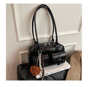 Polished black bowling bag with silver hardware and a brown plush dog charm detail