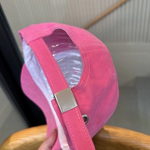 Detailed close-up of adjustable metal buckle and pink cotton strap on baseball cap
