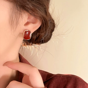 Close-up of elegant gold-framed red square earrings worn by a model in vintage style