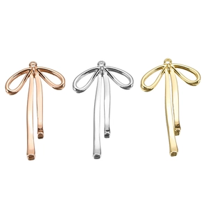 Detail of bow-shaped ribbon pendants in gold, silver, and rose gold finishes for jewelry DIY