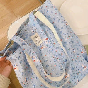 Detailansicht des Blumen-Hasen-Musters und des Innenetiketts der hellblauen Baumwolltasche