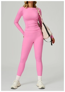 Détail du haut de yoga rose à manches longues avec coutures froncées et legging à poche latérale