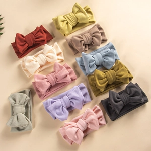 Flat lay of 10 assorted colors baby knit headbands with large soft bow detailing