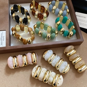 Detailed shot of chunky acrylic marble beads and gold metallic links on a wooden tray