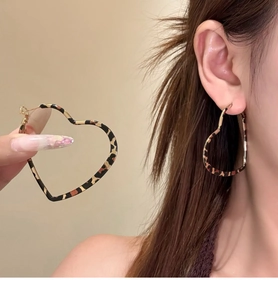 Macro detail and model view of vintage leopard print heart-shaped hoop earrings