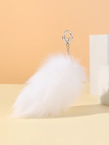 Close-up of a fluffy white faux fur fox tail keychain with silver metal ring attachment