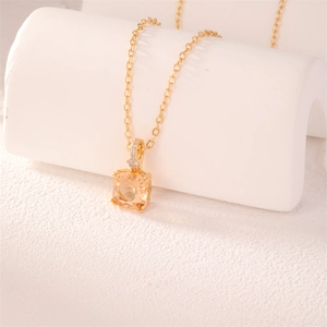 Close-up of elegant gold necklace with square champagne zircon pendant and small crystals