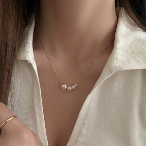 Détail du collier plaqué or avec cinq perles de tailles variées porté par un mannequin