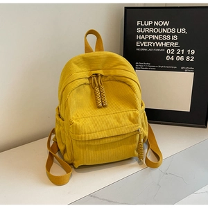 Detail of yellow corduroy texture and front zipper pocket on a stylish small backpack